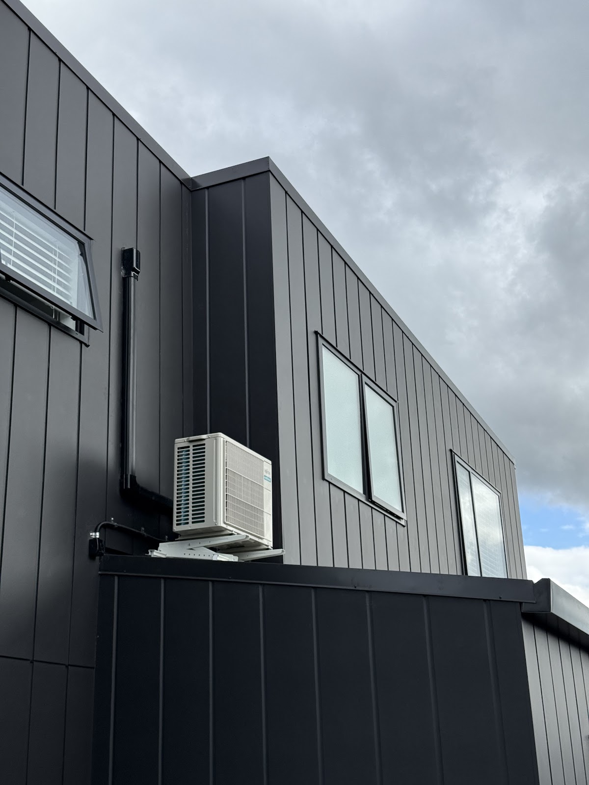 Heat pump outdoor unit mounted and wired on exterior cladding